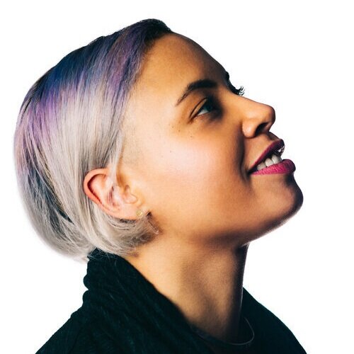 A woman with purple-silver ombre hair in a bob in profile